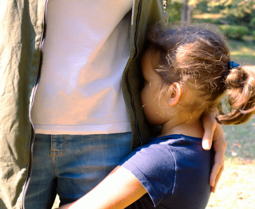 Little girl feeling sad and embracing her mother at the park.